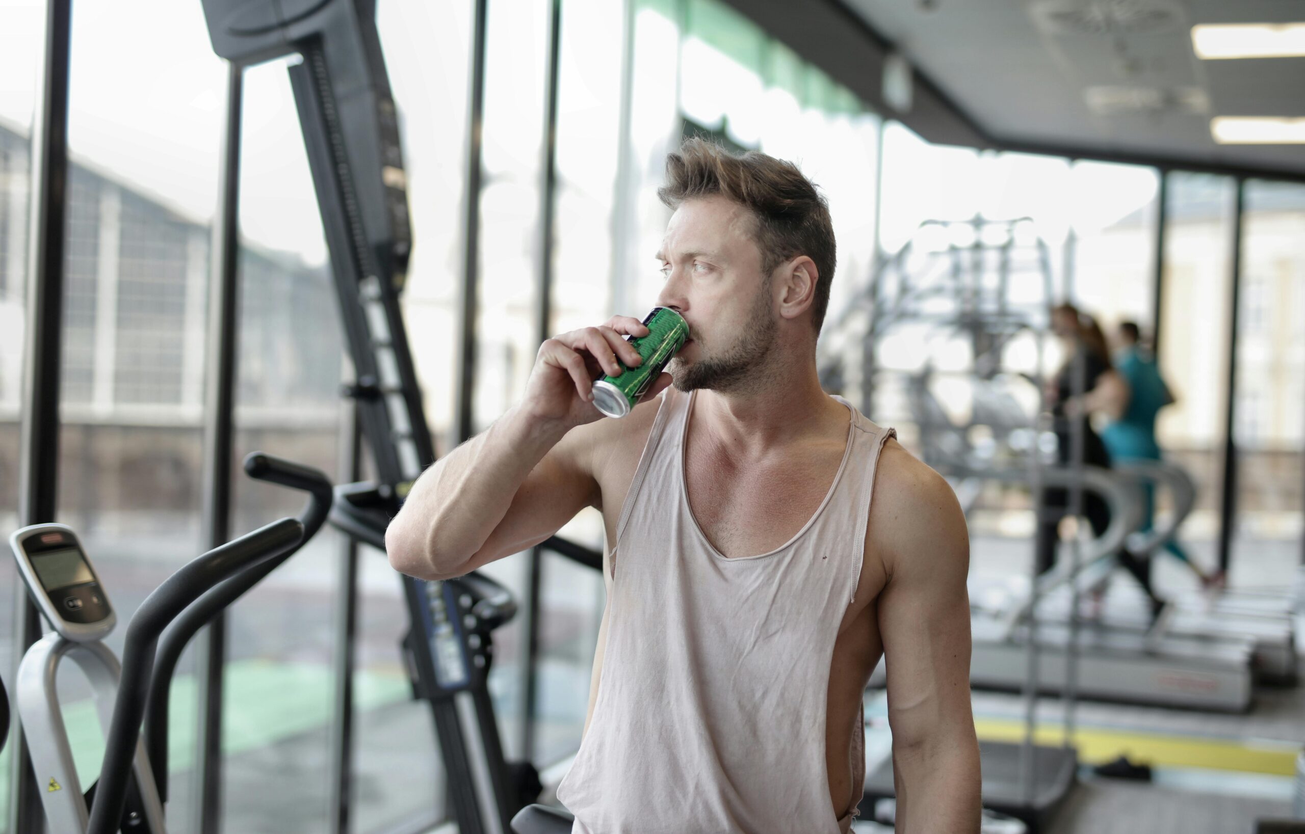 Müder Junger Männlicher Athlet, Der Energiegetränk Beim Ausruhen Nach Dem Training Im Fitnessstudio Trinkt